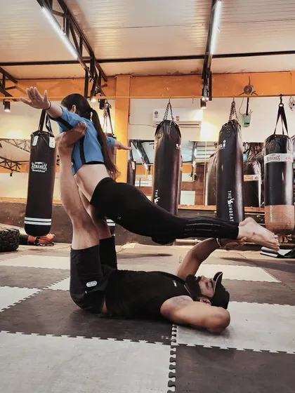 A classic Acro Yoga pose often called "bird." It looks graceful, but it requires the base to have strong legs and core while the flyer engages every muscle to stay stable.