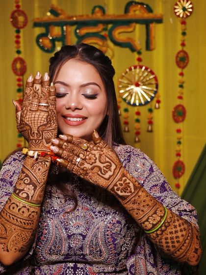 A happy bride with her hands full of mehndi, her makeup soft, stunning, and totally bride-approved.
