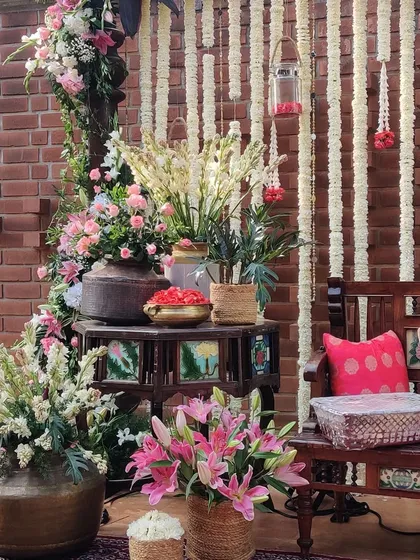 This Mehendi corner combines rustic charm with traditional elegance. We used a brick wall as a backdrop, layering it with hanging tuberose garlands and setting up a cozy seating area with antique brass pots, vibrant pink lilies, and unique tiled furniture.