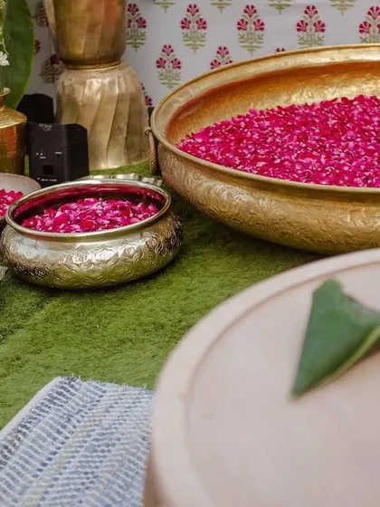 Brass bowls filled with bright pink rose petals, placed along the aisle and around the seating areas, ready for a celebratory flower shower.