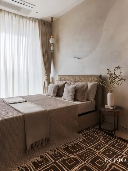 A full view of the bedroom with the sculptural wall, showcasing the cohesive earth-toned palette from the bedding and rug to the curtains and side table.