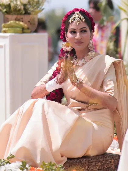 A serene portrait of the bride. Her makeup is elegant and understated, allowing the dramatic floral hairstyle to be the focus.