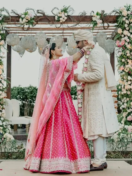 The couple during their varmala ceremony, framed by the beautiful floral pillars of the mandap.