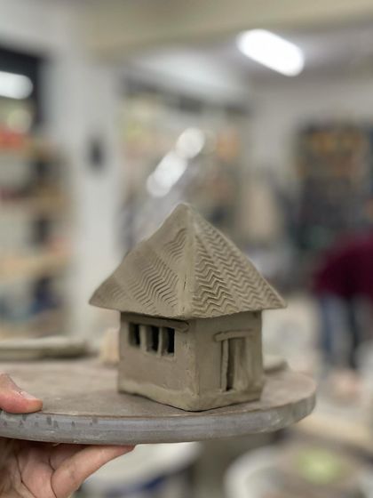 This hand-built clay house, with its textured roof and carved windows, is a perfect example of what you can create in our workshops.
