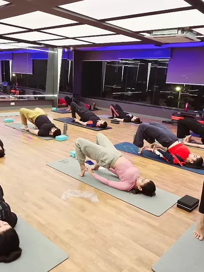 A class practicing Setu Bandhasana (Bridge Pose). This pose strengthens the back muscles, opens the lungs, and calms the brain, reducing stress and anxiety.