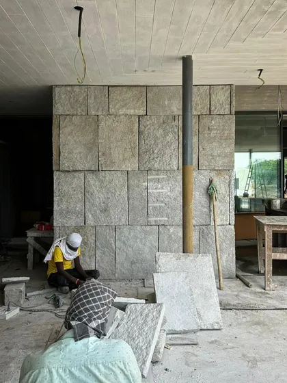 An artisan works on the granite wall inside one of our Alibaug houses. The careful cutting and placement of each stone block is essential to achieving the desired texture and pattern.