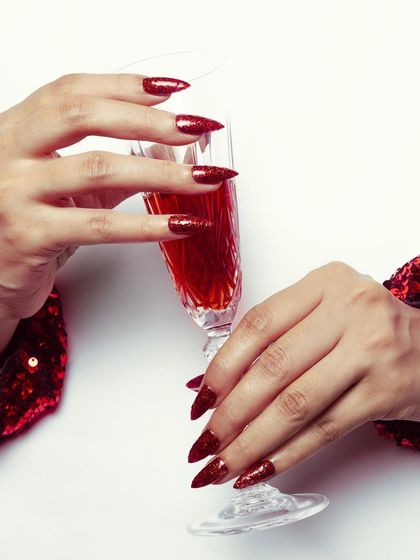 A glamorous set of sharp, stiletto-shaped nails with full-coverage red glitter. This is the ultimate party nail, perfect for festive seasons and special events.