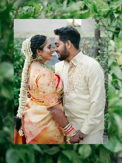A romantic close-up of the couple, framed by lush green leaves for a natural, intimate feel.