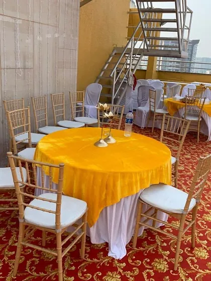 Seating arrangement for a terrace party in Bandra. We used round tables with bright yellow tablecloths and elegant chairs to set up a comfortable dining or seating area for guests.