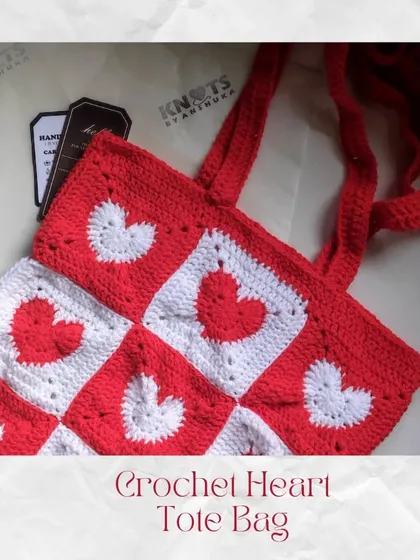 A flat lay of the crochet heart tote bag, showing the pattern of alternating red and white heart granny squares. Each square is stitched together by hand.