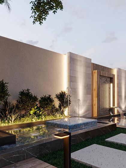 A beautiful shot of the multi-level water features in this backyard. The design combines a gentle fountain, a cascading waterfall, and a larger pool, all surrounded by carefully selected plants and elegant lighting.