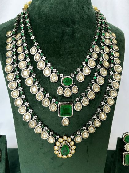 A layered bridal necklace set with three distinct strands, all featuring green stones and Kundan work. This rental set offers a very regal appearance.