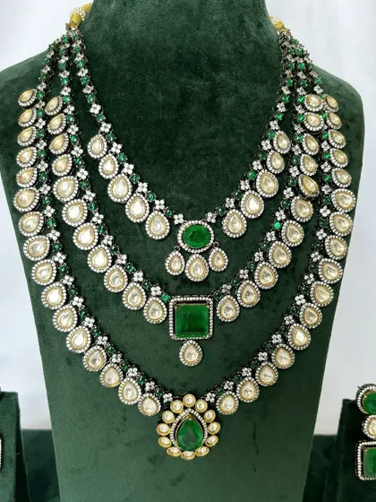A layered bridal necklace set with three distinct strands, all featuring green stones and Kundan work. This rental set offers a very regal appearance.