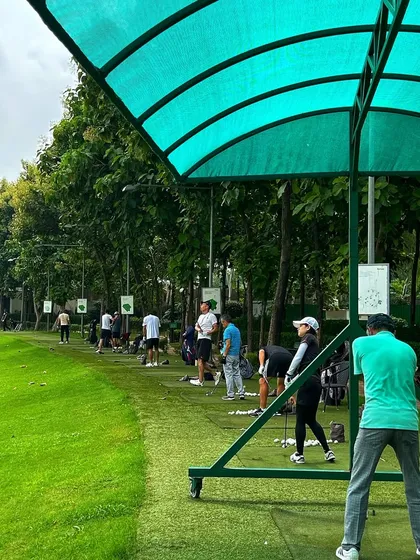 From under the green canopy, golfers take aim. The covered bays provide shade and comfort during practice.