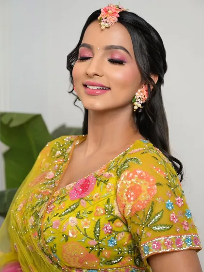 A close-up of a vibrant Haldi or Mehendi look, with bright pink eyeshadow that perfectly matches the floral details in her outfit.