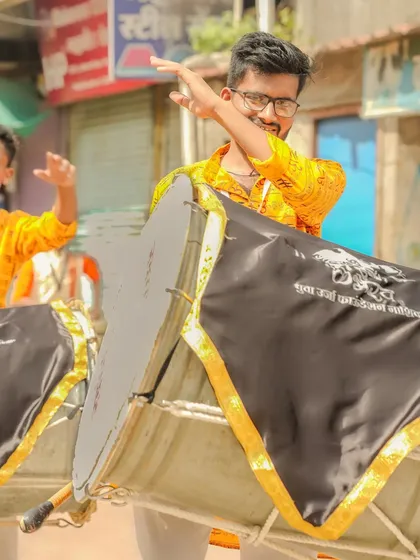 A dhol player with a smile and a playful gesture.