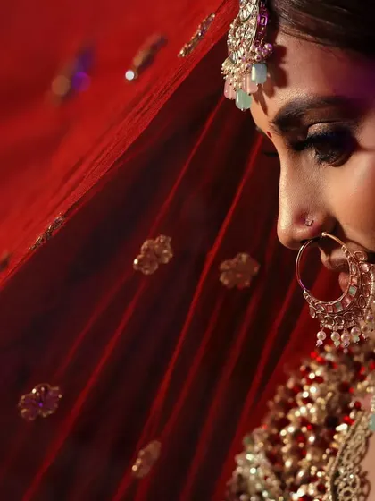 The true beauty of a bride lies in the eyes of the groom. This close up shot, with the red dupatta creating a soft frame, highlights her delicate features and bridal glow.