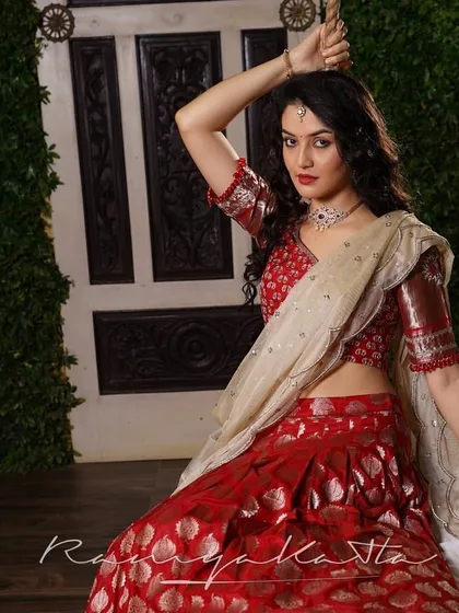A dynamic pose showcasing the beautiful fall of the cherry red Benaras lehenga and the sparkle of the rose gold embroidered blouse.