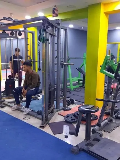 The cable crossover machine is a versatile tool for hitting muscles from different angles. Here, a member takes a rest between sets, with the rest of the gym's strength equipment visible.