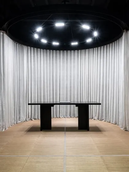 Inside one of the revealed pods, a minimalist work desk stands as a functional centerpiece. The circular track lighting above provides focused illumination, creating a distinct, task-oriented zone that remains connected to the overall aesthetic of the luxury bedding store.