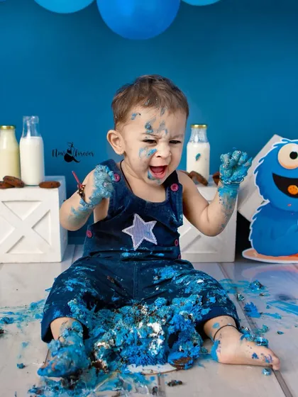 The face of pure, messy delight! This candid shot perfectly captures the sensory experience and fun of a first birthday cake smash.