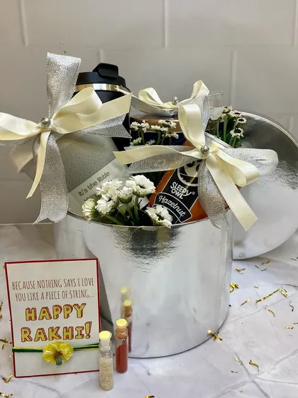 A sleek silver-themed Rakhi hamper, perfect for a brother or sister. It comes with a shaker bottle and other treats, all tied together with a beautiful silver ribbon.