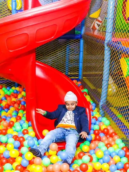 A vibrant shot of our massive red spiral slide, where kids can zip down into a sea of colorful balls. This is one of the main attractions in our multi-level soft play area, promising endless fun.