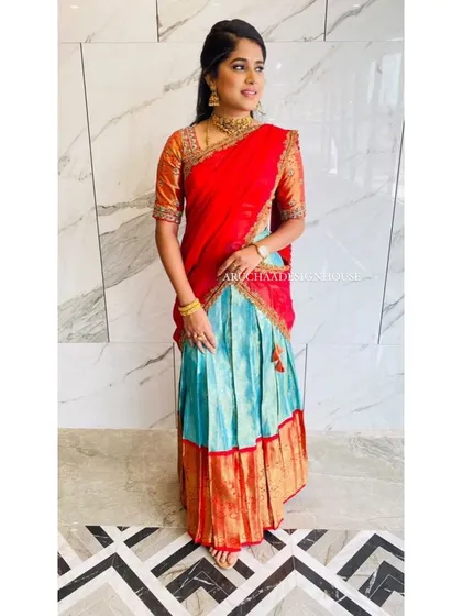 A beautiful client glowing in a custom-designed half saree. We repurposed her traditional saree into this vibrant red and turquoise langa voni, perfect for wedding festivities. The rich colors and classic silhouette make it a timeless piece.