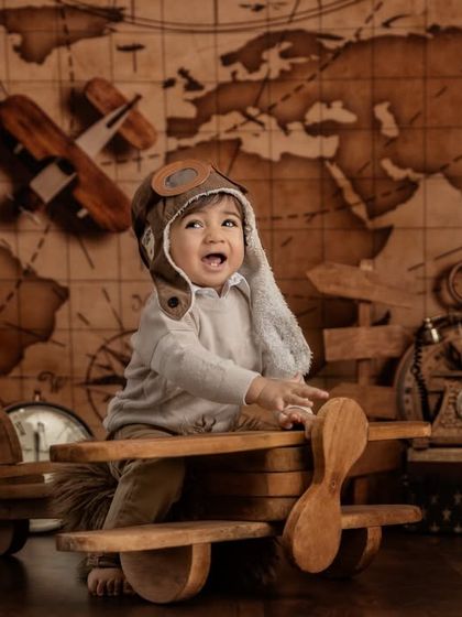 Adventure awaits. This little aviator is ready for takeoff in a vintage-themed shoot, complete with a wooden airplane, an old-world map, and classic props.