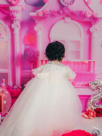 A lovely shot from the back, showing the beautiful details and bow on her white party dress.