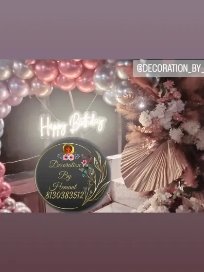 A close-up view of a modern birthday balloon arch. The mix of metallic rose gold and silver balloons, paired with a 'Happy Birthday' neon sign, creates a stylish and warm glow for the celebration.