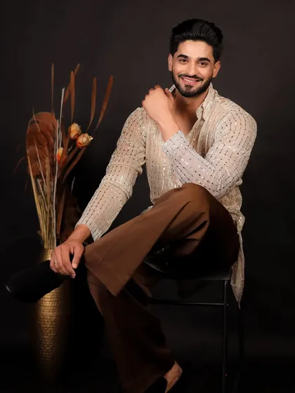 A relaxed and smiling portrait of a male model in a modern kurta, shot in the studio.