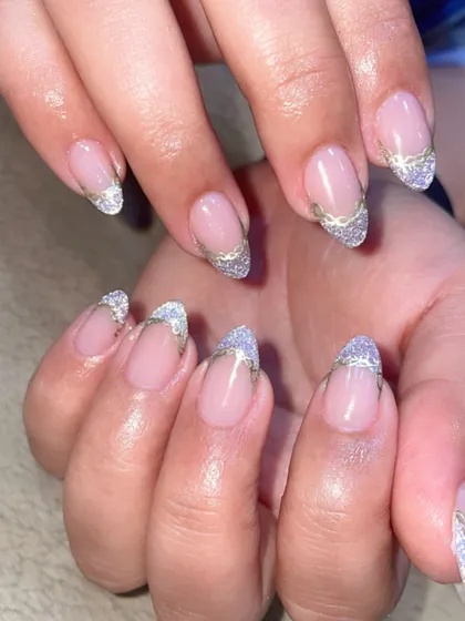 A glamorous take on the French manicure. The tips are adorned with sparkling silver glitter and a delicate gold line for a touch of elegance.