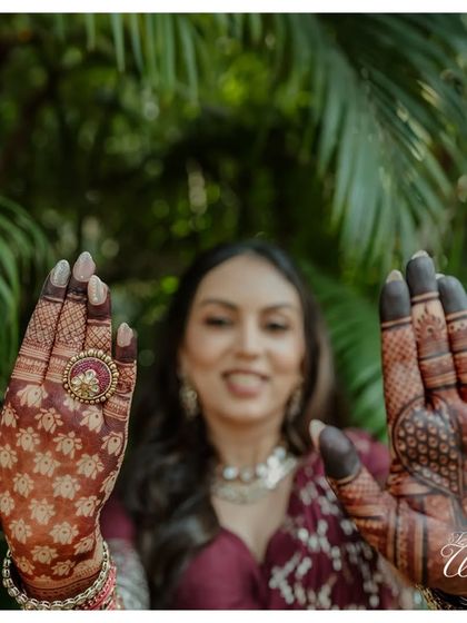 A creative shot showcasing the intricate Mehendi design. The bride's hands, rich with henna, are the focus, symbolizing the beauty and artistry of this pre-wedding tradition.