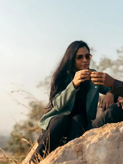 Sharing a toast with chai on a rocky outcrop. This photo captures a simple, happy moment during their outdoor adventure, celebrating their love with a shared ritual.