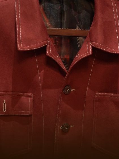 A full view of the crimson suede shacket, showing its clean lines and contrast stitching. This is a versatile piece that combines the structure of a jacket with the ease of a shirt.