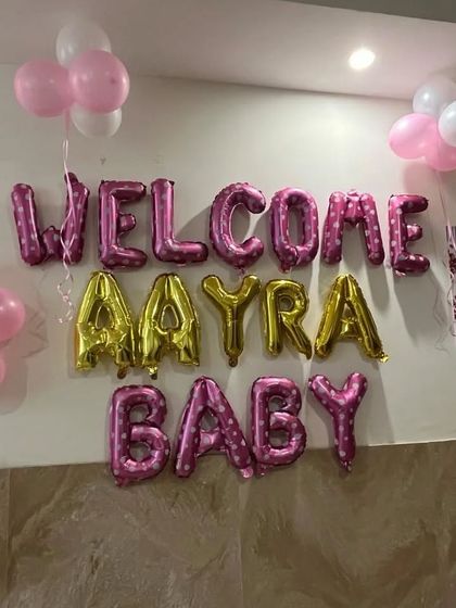 I can personalize the welcome message with your baby's name. This setup for baby Aayra uses a mix of pink and gold foil balloons to make her feel extra special.