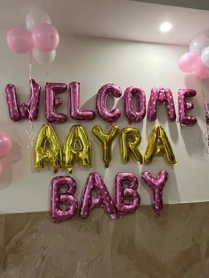 I can personalize the welcome message with your baby's name. This setup for baby Aayra uses a mix of pink and gold foil balloons to make her feel extra special.