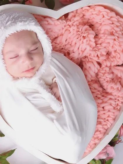 A detailed close-up of the baby's face, capturing the peacefulness of sleep amidst the soft pink roses.