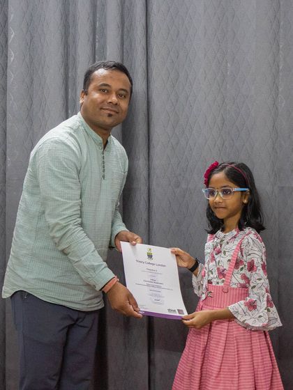 A young student receives her Trinity College London certificate for her performance.