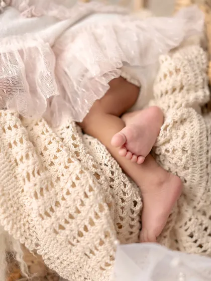 It's all in the details. This close-up on the tiny feet of a newborn resting on a soft, crocheted blanket is a reminder of how small they start.