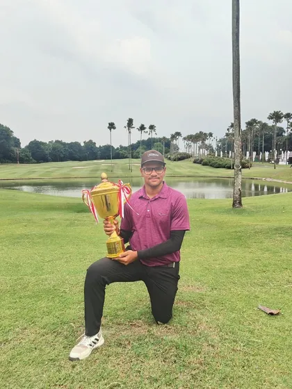 Harman kneels with his impressive winner's trophy on the course in Jakarta after winning the 4th International Jr Menpora PAGI EMERALDA Golf Championship.
