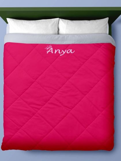 The pink version of our quilted comforter, shown spread out on a bed. It's a beautiful and practical addition to any bedroom.