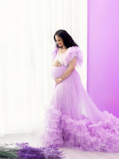 A vision in lavender. This portrait features a beautiful ruffled gown against a matching backdrop with hanging wisteria, creating a soft, floral-inspired fantasy.