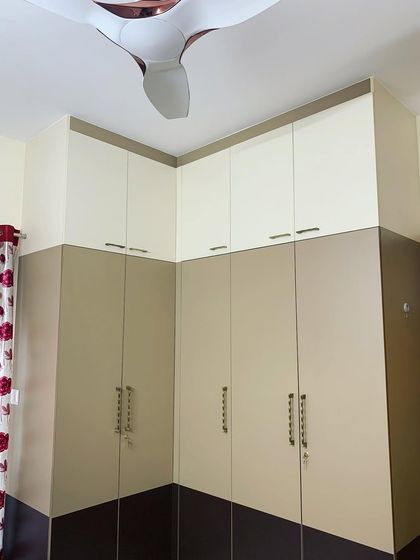 This corner wardrobe in the master bedroom uses a dual-color laminate scheme to add visual interest. The floor-to-ceiling design maximizes storage space in the room.