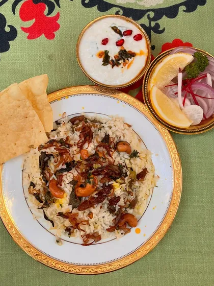Another look at our Malabar Biryani, served with cooling raita and a fresh onion salad. The crispy papadom adds the perfect crunch to this flavourful Iftar dish.