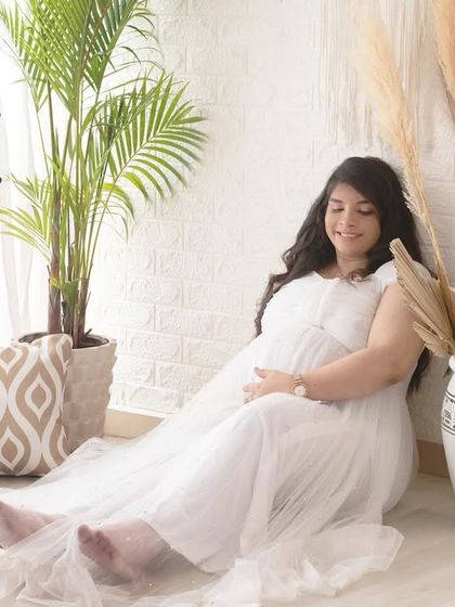 A serene solo portrait in a beautiful white gown. The bright, airy feel of this boho setup with its plants and pillows creates a peaceful and relaxed setting.