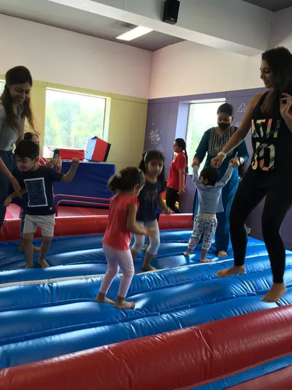 Parents join in on the fun. Here, moms help their little ones bounce and play on the inflatable tumble track during a special camp activity.