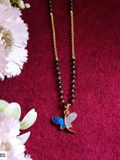 A delicate and modern mangalsutra design, this piece features a butterfly pendant with blue enamel and diamond accents. It's crafted from 92.5 silver with gold plating.