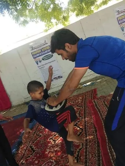 A trainer helps a young boy practice knee strikes on a pad, a vital technique for close-range self-defence.